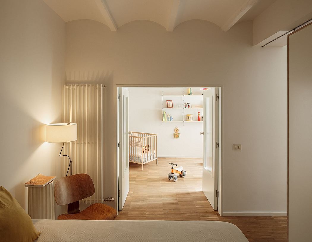 Cozy nursery room with arched ceilings, wooden floors, and a crib visible in the adjoining room.
