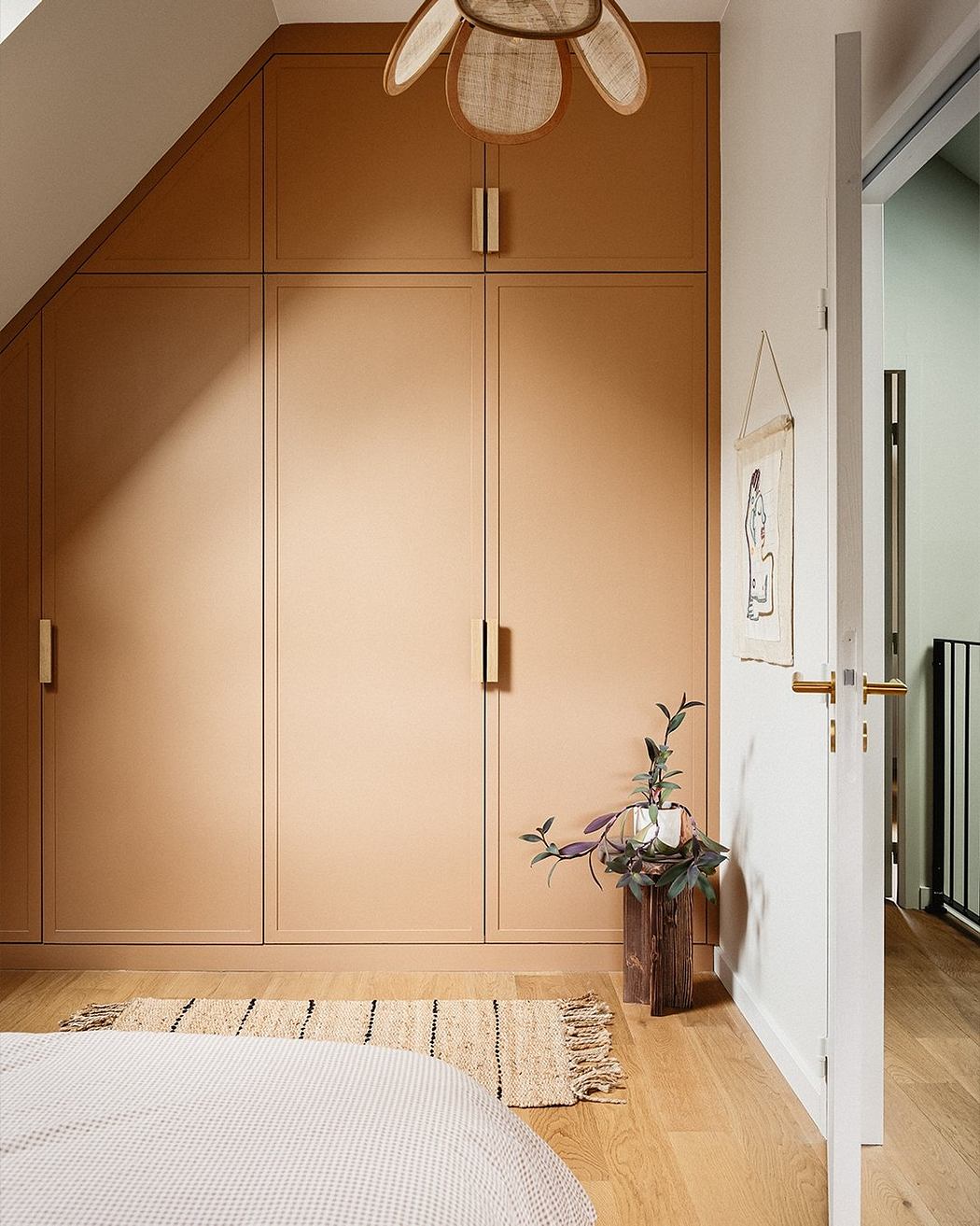 Warm-toned, paneled cabinetry with a sculptural pendant light in a cozy bedroom.
