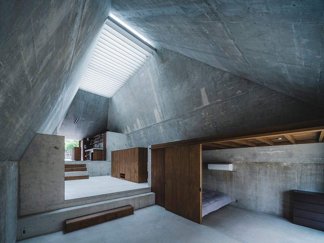 An interior space with a sloping, concrete ceiling, wooden cabinets, and elevated levels.