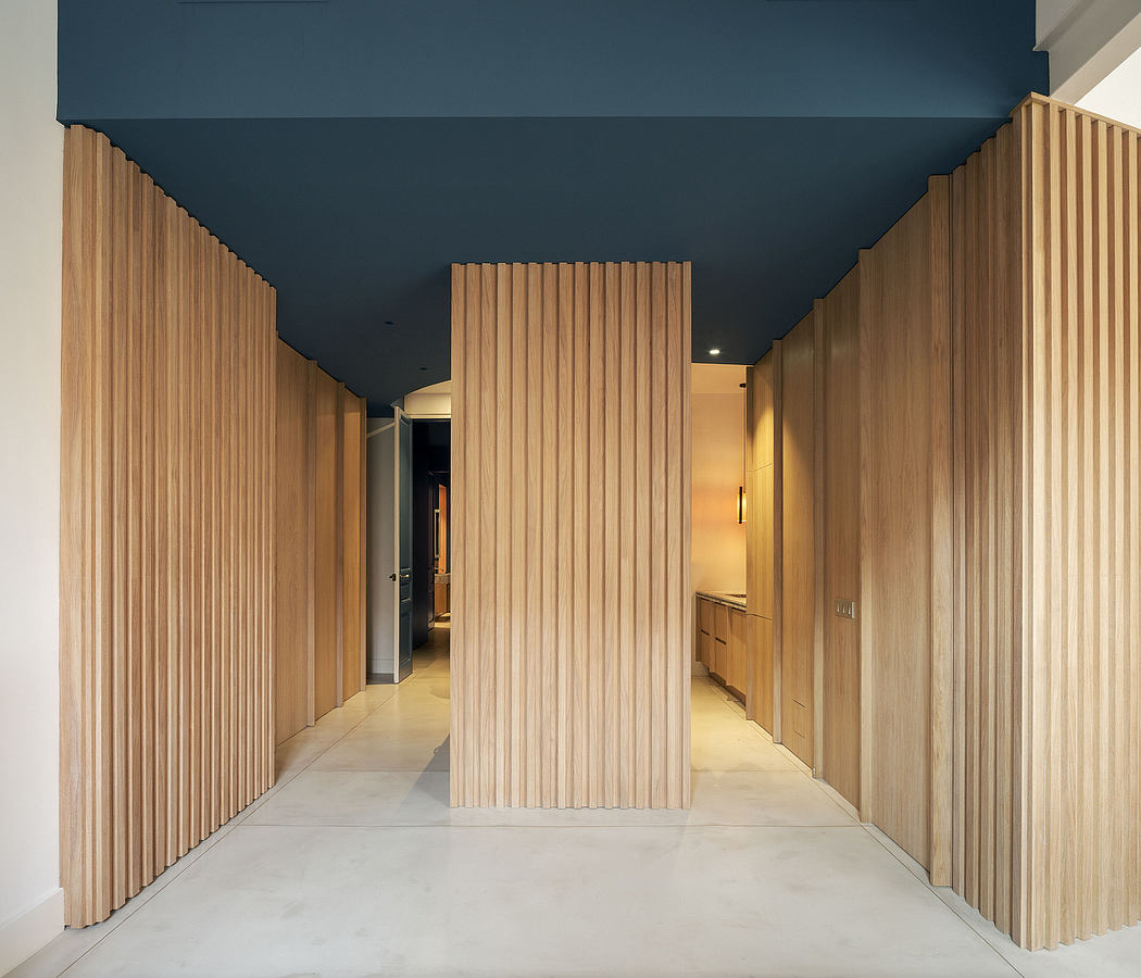 A modern, minimalist corridor featuring wood paneling and a dark blue ceiling.