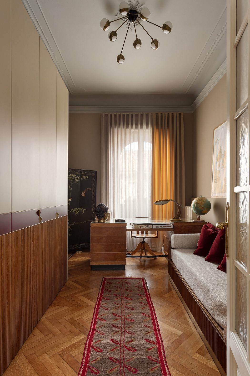 Elegant mid-century modern workspace with patterned rug, wooden furniture, and striking chandelier.