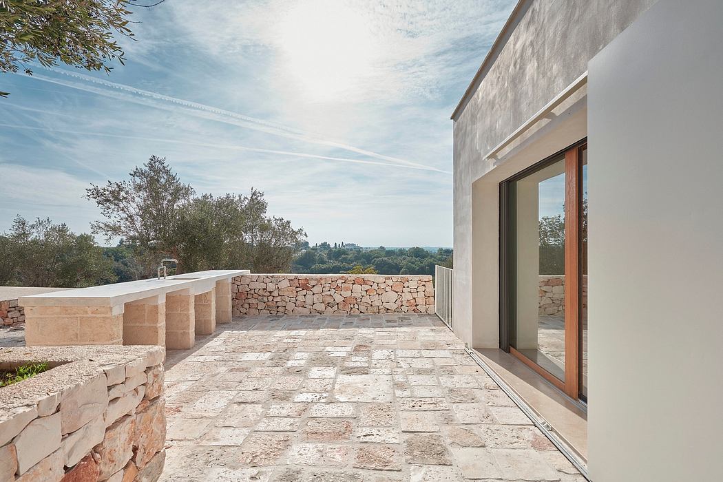 A modern concrete and stone villa with a large terrace overlooking lush greenery.