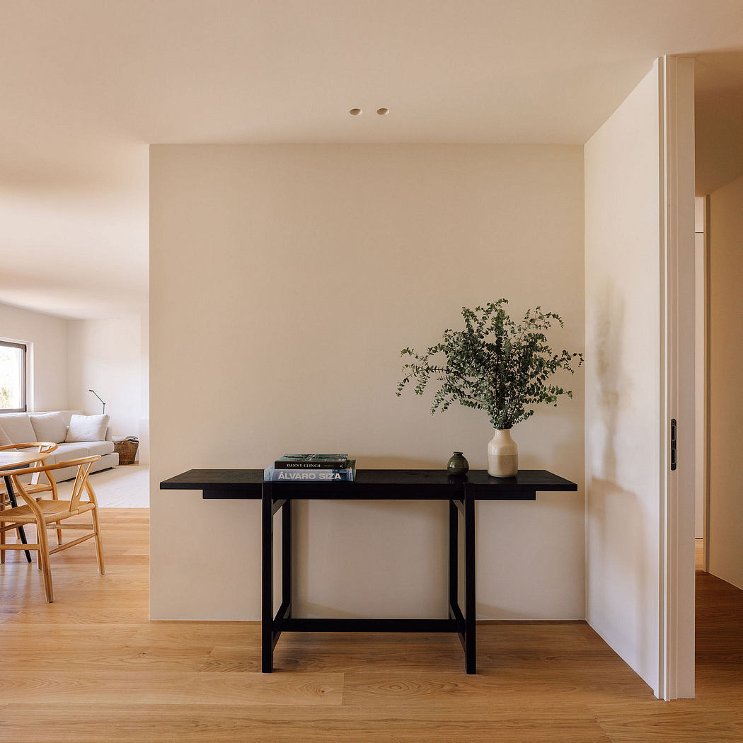 Minimalist entryway with black console table, vase of greenery, and hardwood flooring.