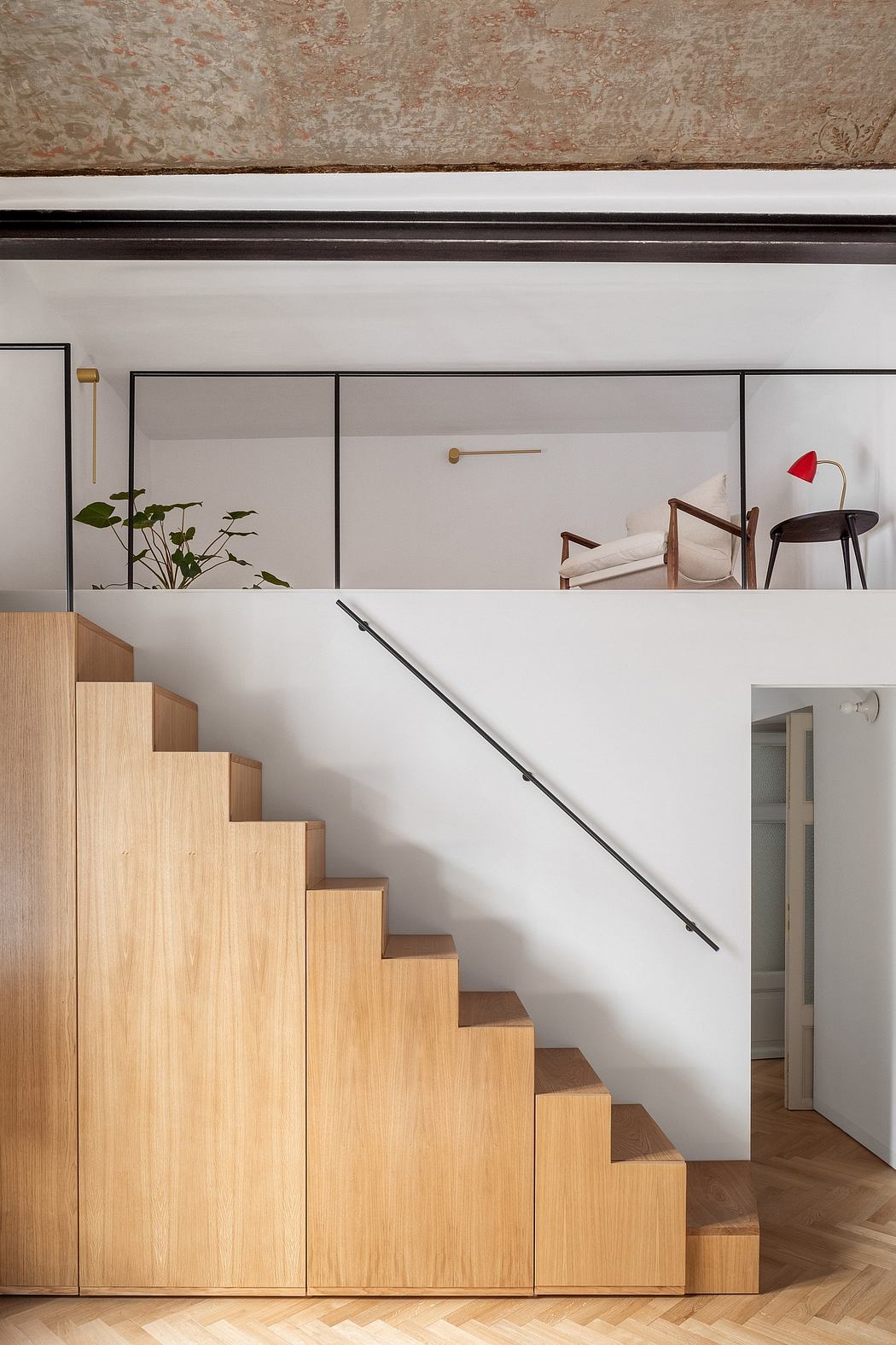 Minimalist interior with modern wood staircase, white walls, and brass accents.