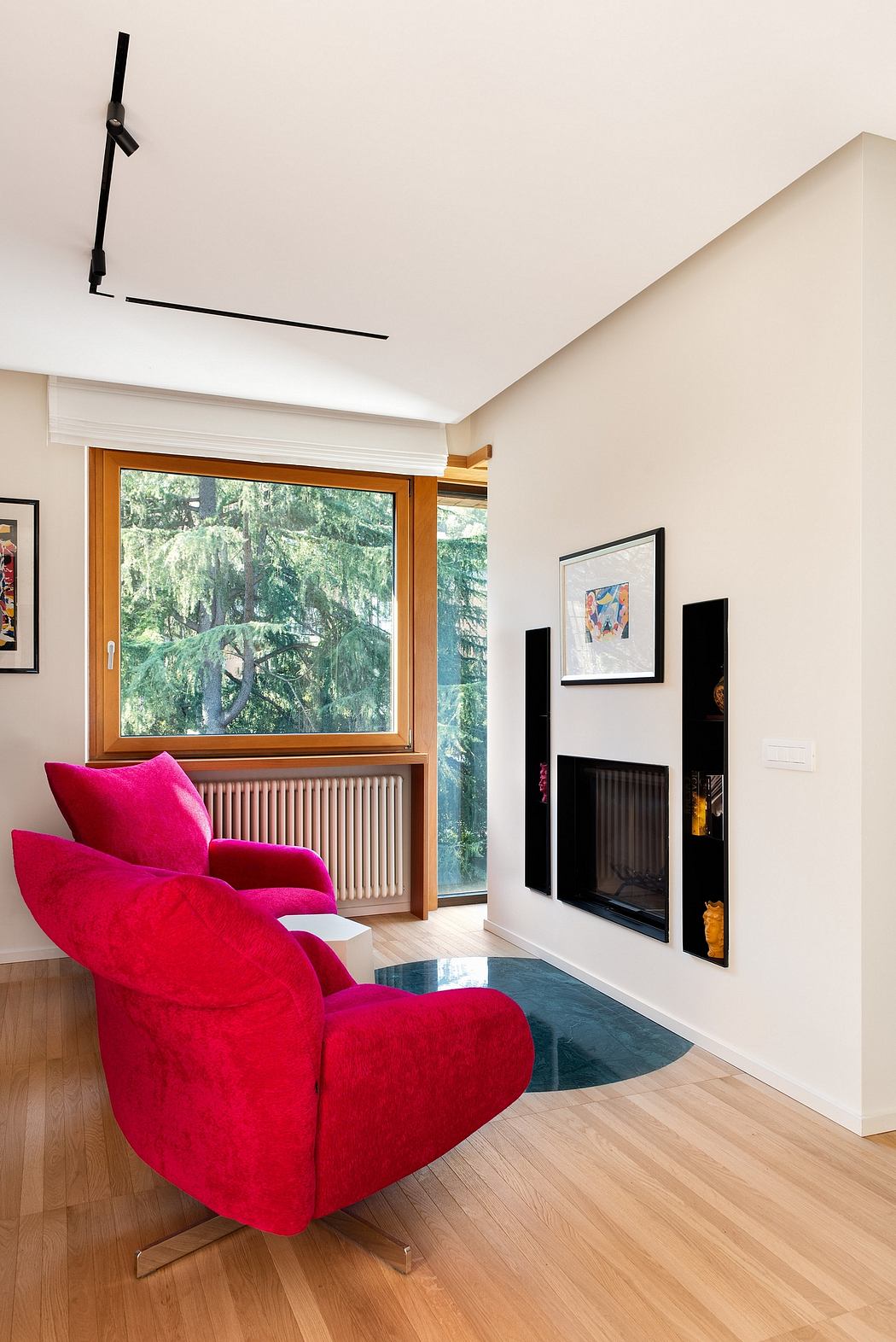Cozy living room with vibrant red chair, wooden window frame, and modern fireplace.