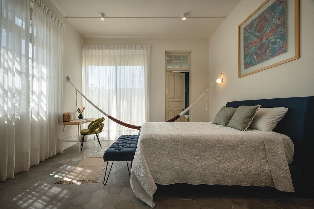 Cozy bedroom with plush bedding, exposed beams, art piece, and hexagonal tile flooring.