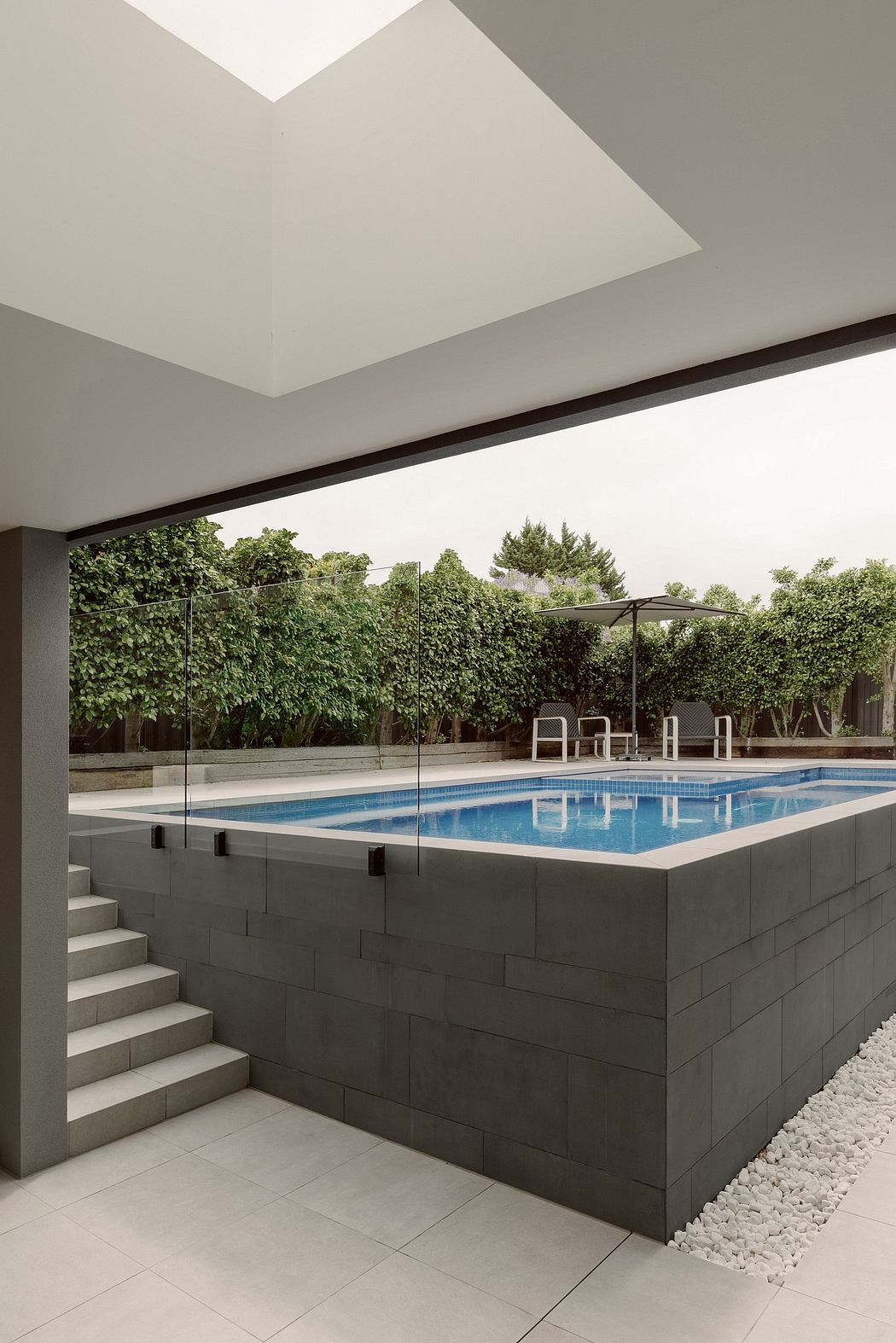 Sleek, contemporary pool design with minimalist architecture and lush greenery backdrop.