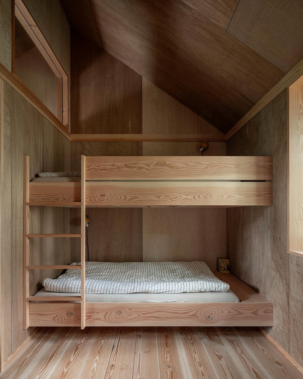 Cozy wooden bunk beds with storage shelves in a rustic cabin interior.