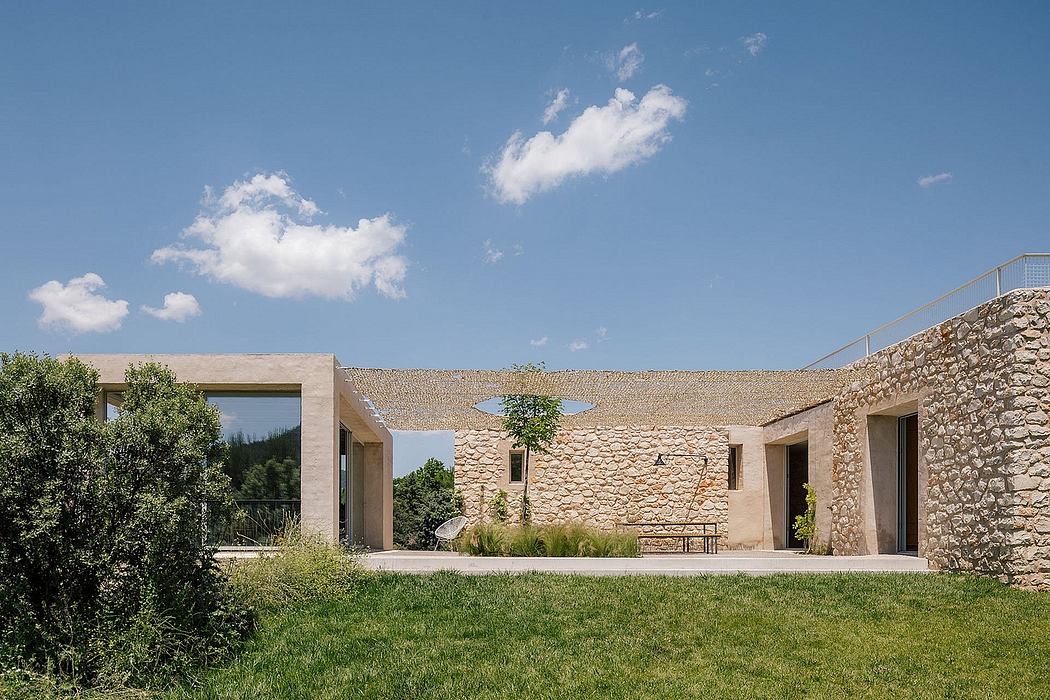 A modern, stone-walled building with a grassy courtyard and glass windows.