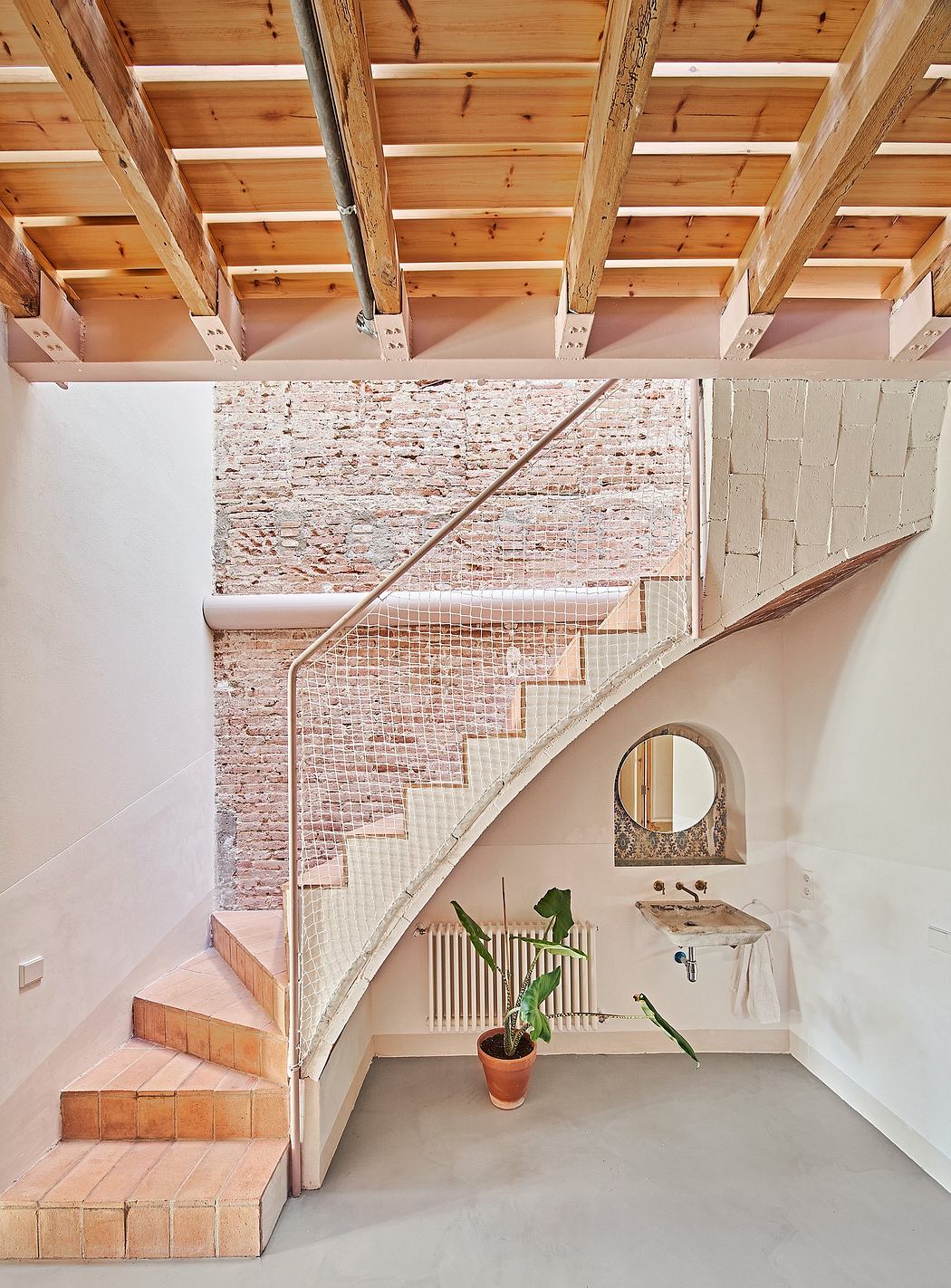 Wooden beams, brick wall, metal railings, and curved staircase in a modern interior.