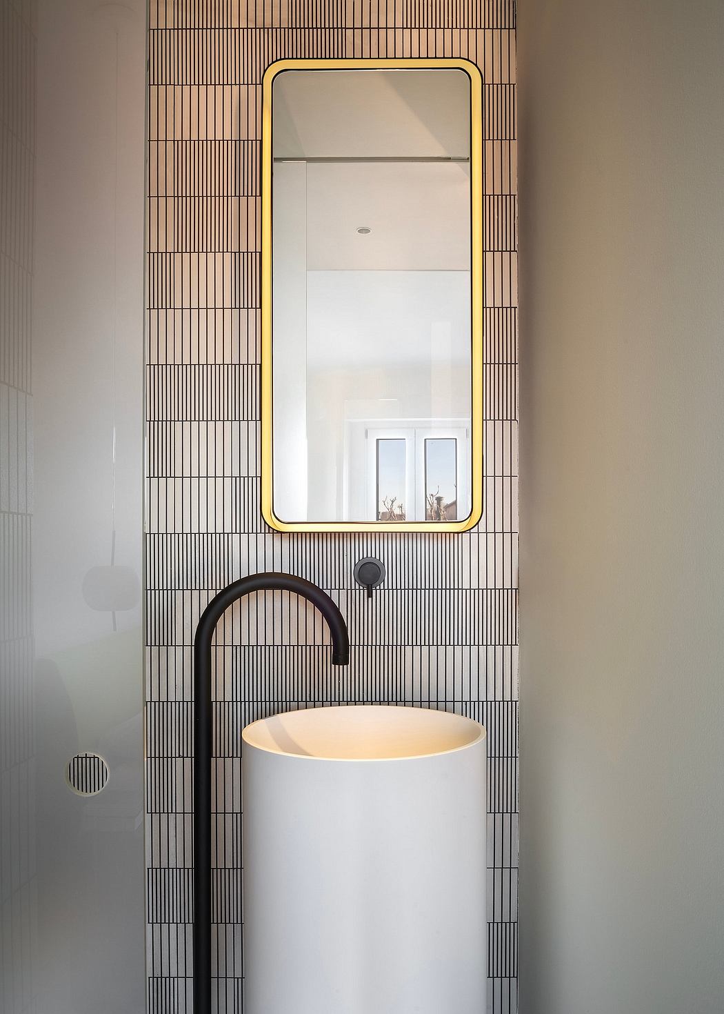 Sleek, minimalist bathroom with striking black faucet, white sink, and patterned tile wall.