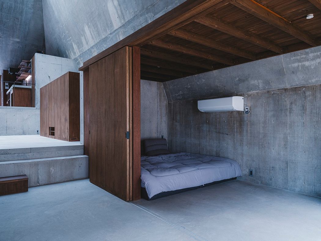 Minimal, industrial-style bedroom with wooden built-in furniture and concrete walls.