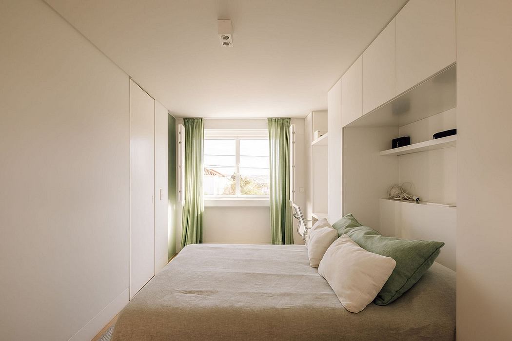 A cozy, minimalist bedroom with white walls, green curtains, and built-in storage.