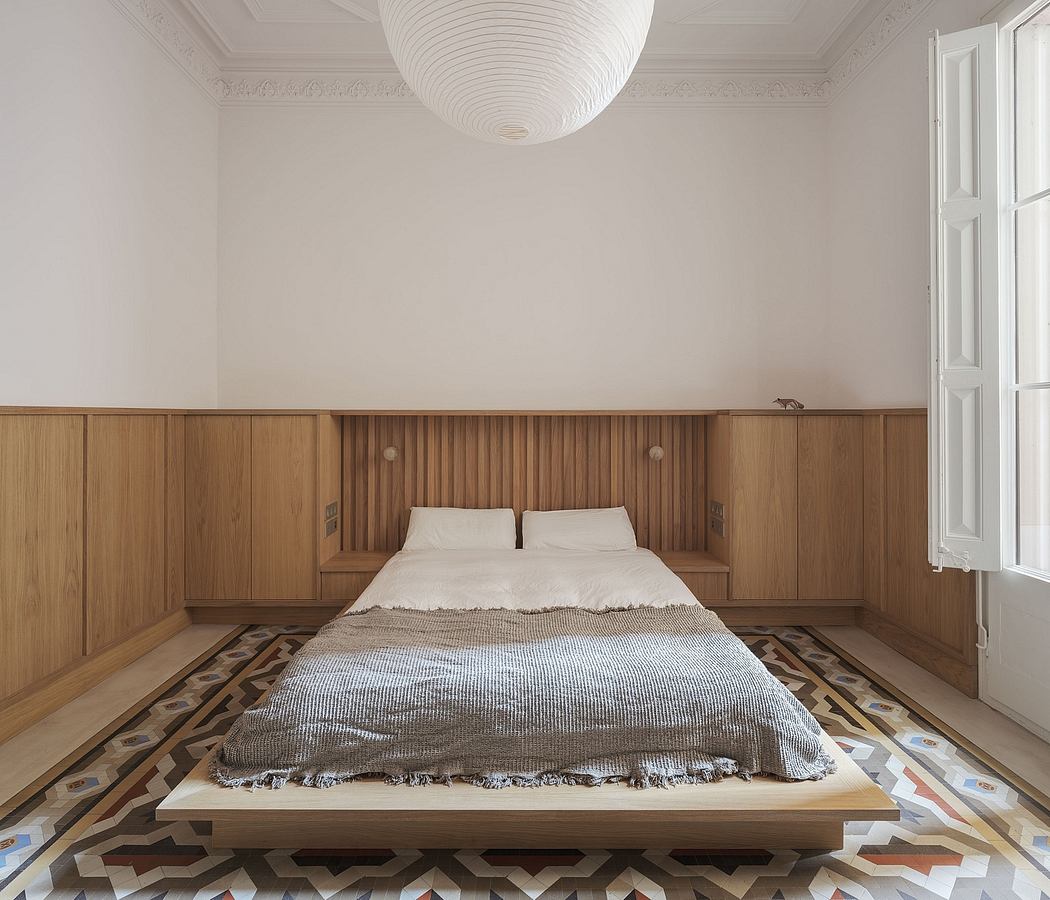 A spacious bedroom with a modern, minimalist design featuring wooden panels and patterned floors.