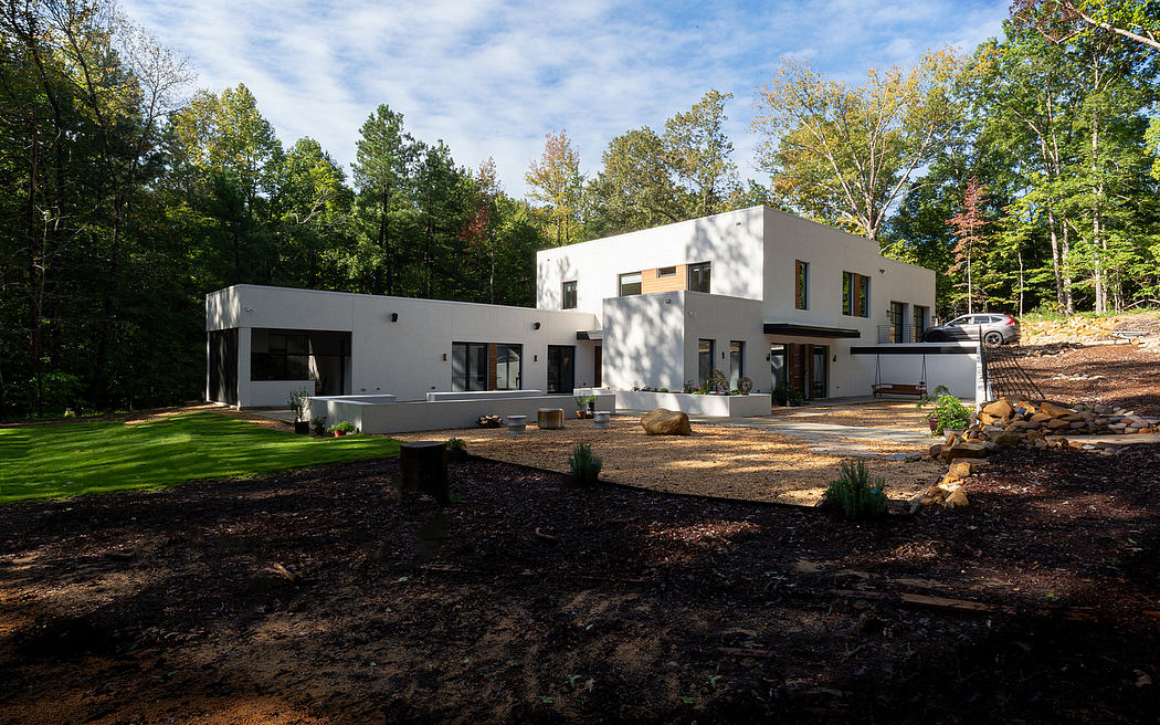 Striking modern home nestled in lush forest, with clean lines, large windows, and landscaped yard.