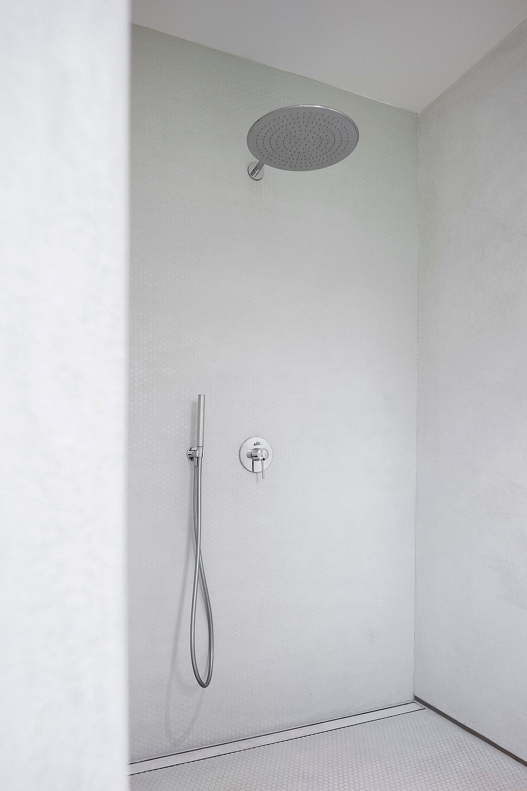 A minimalist shower design with a large round showerhead and a wall-mounted faucet.
