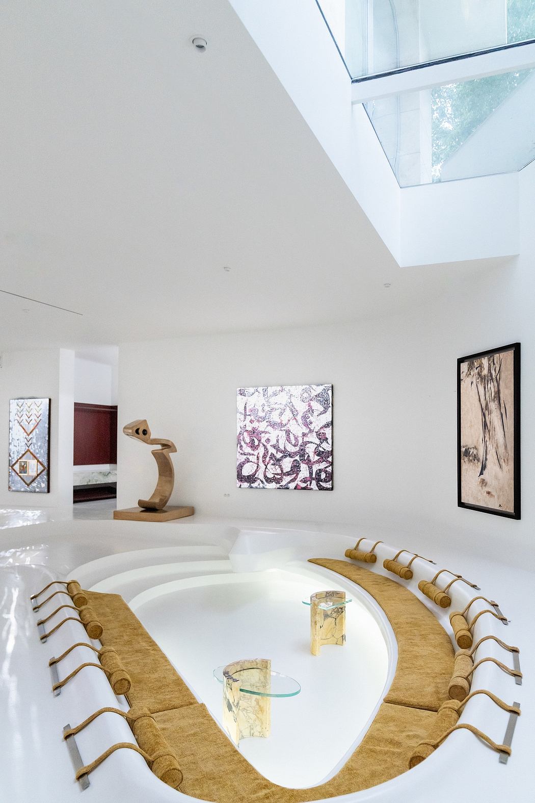 Minimalist white room with angular wooden furniture and abstract artwork.