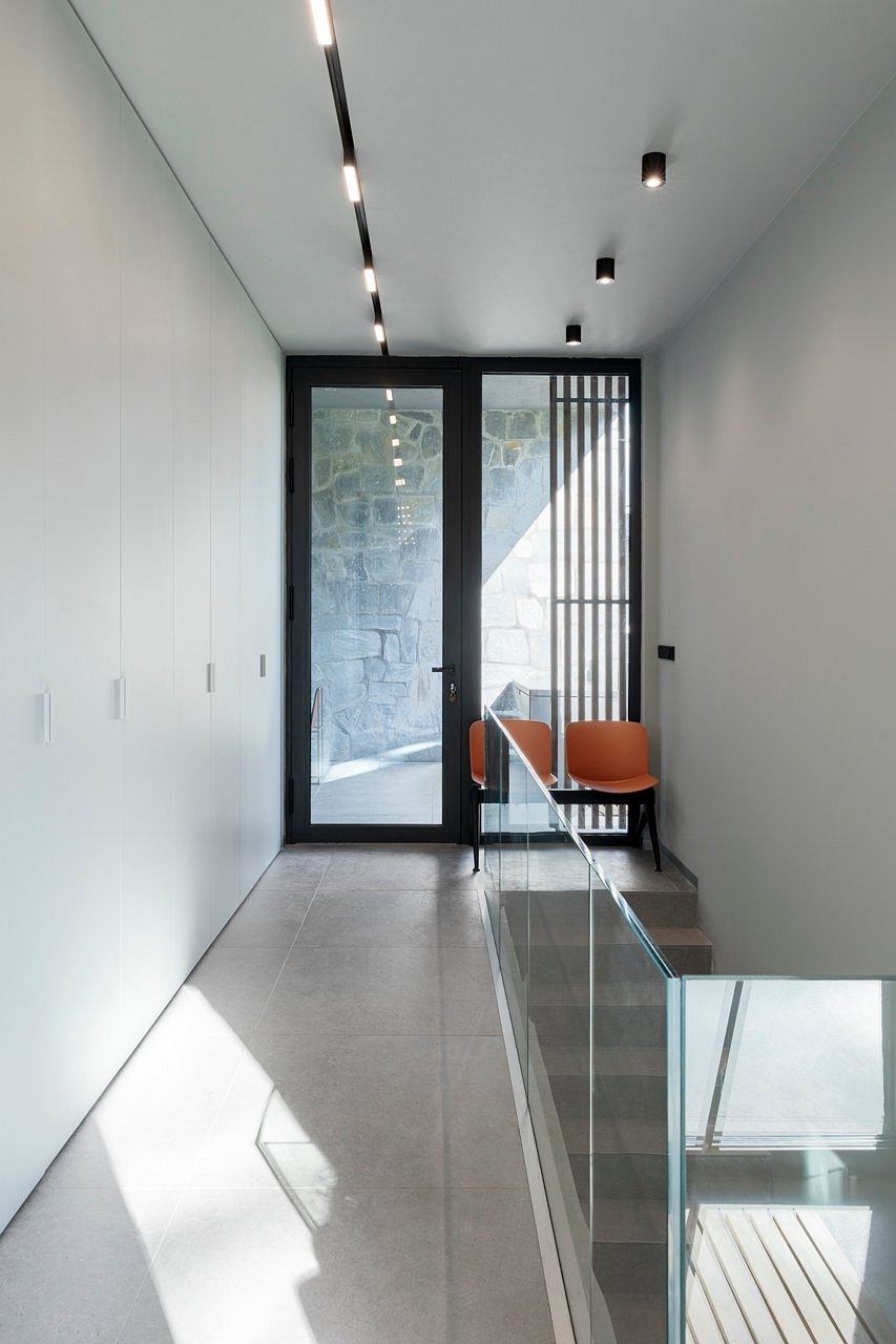 Minimalist entryway with a glass door, concrete floor, and modern light fixtures.
