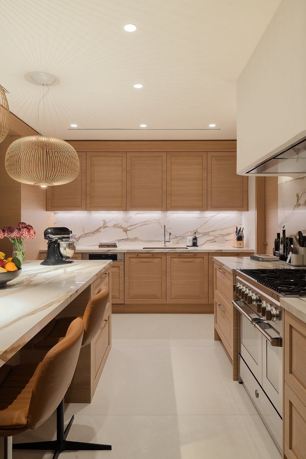 Sleek wood cabinetry, marble countertops, and pendant lighting in a modern kitchen.