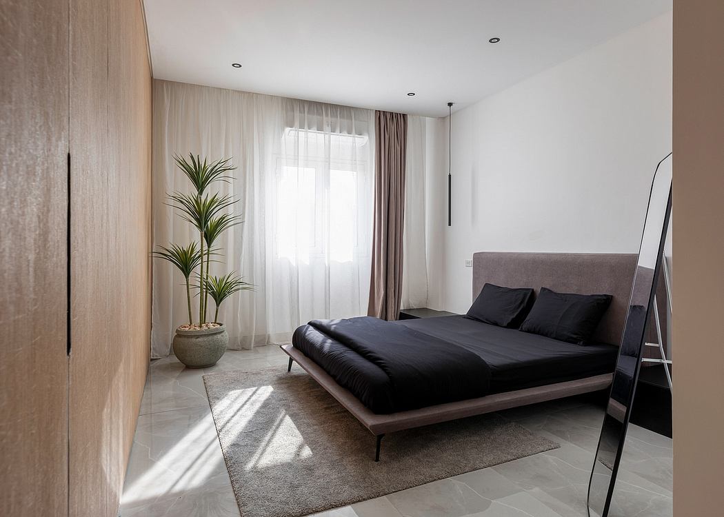 Spacious modern bedroom with large windows, gray bedding, and potted plants.