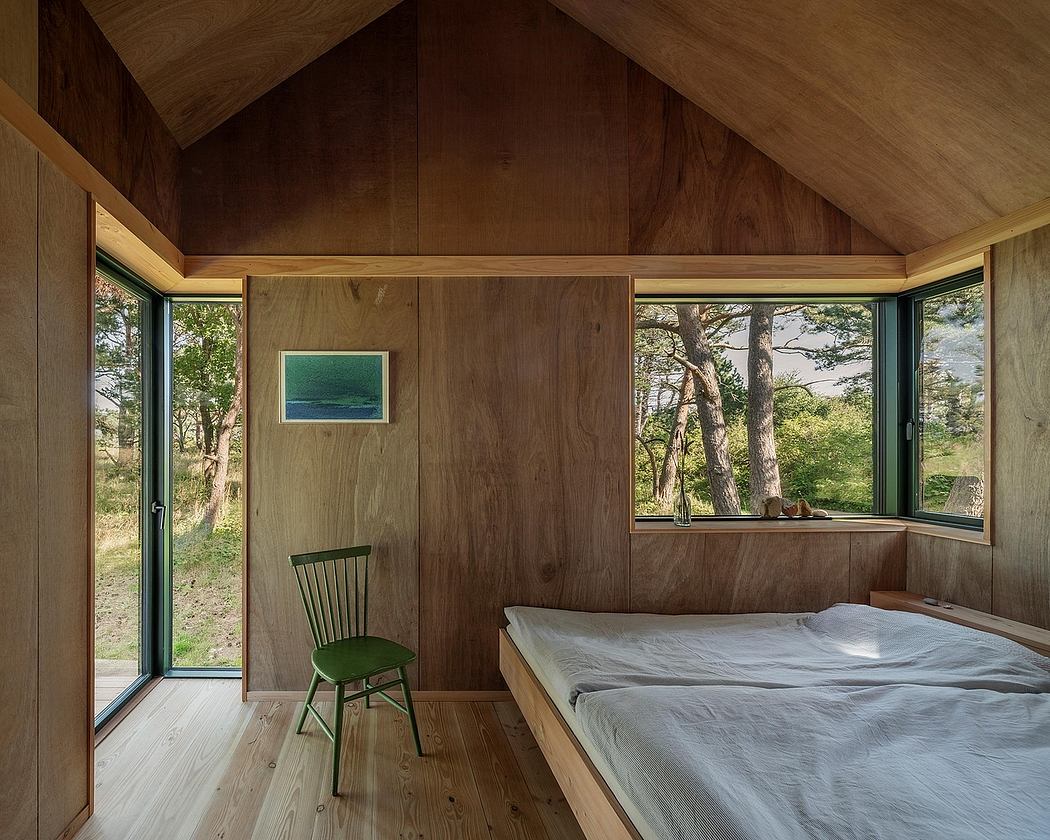 A cozy woodland cabin interior with a vaulted wooden ceiling, large windows, and a comfortable bed.