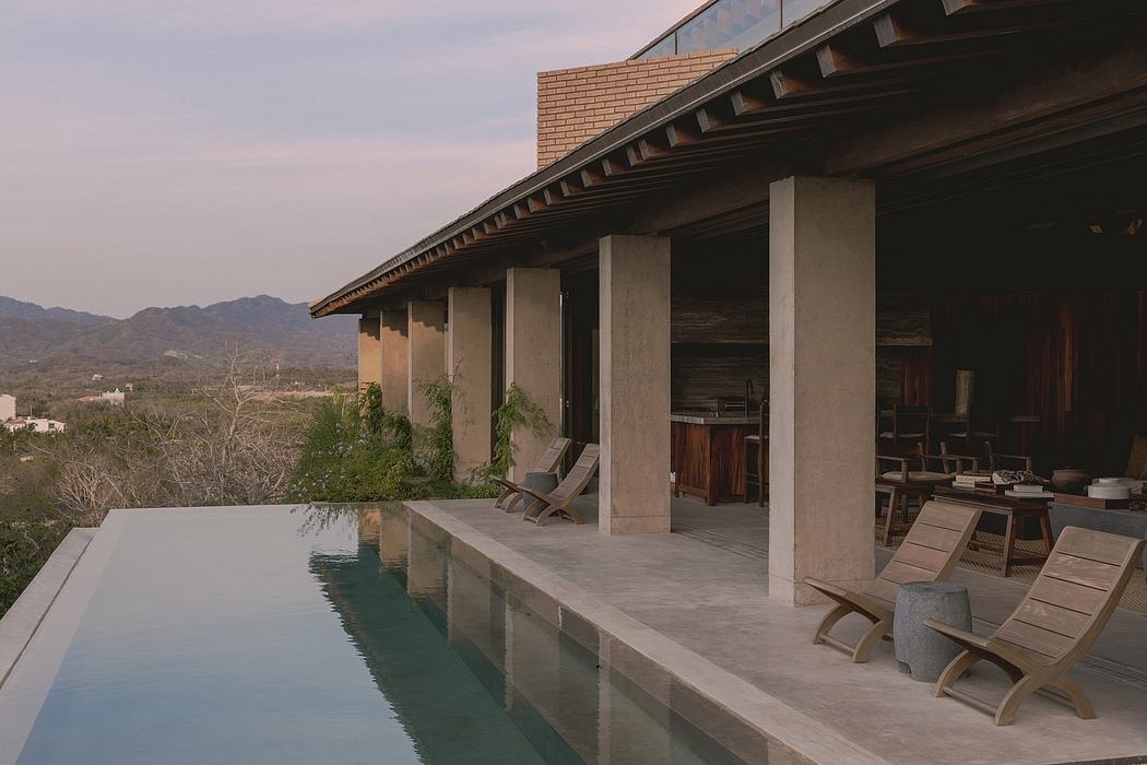 Expansive concrete patio with pool, lounge chairs, and wooden details overlooking mountainous landscape.