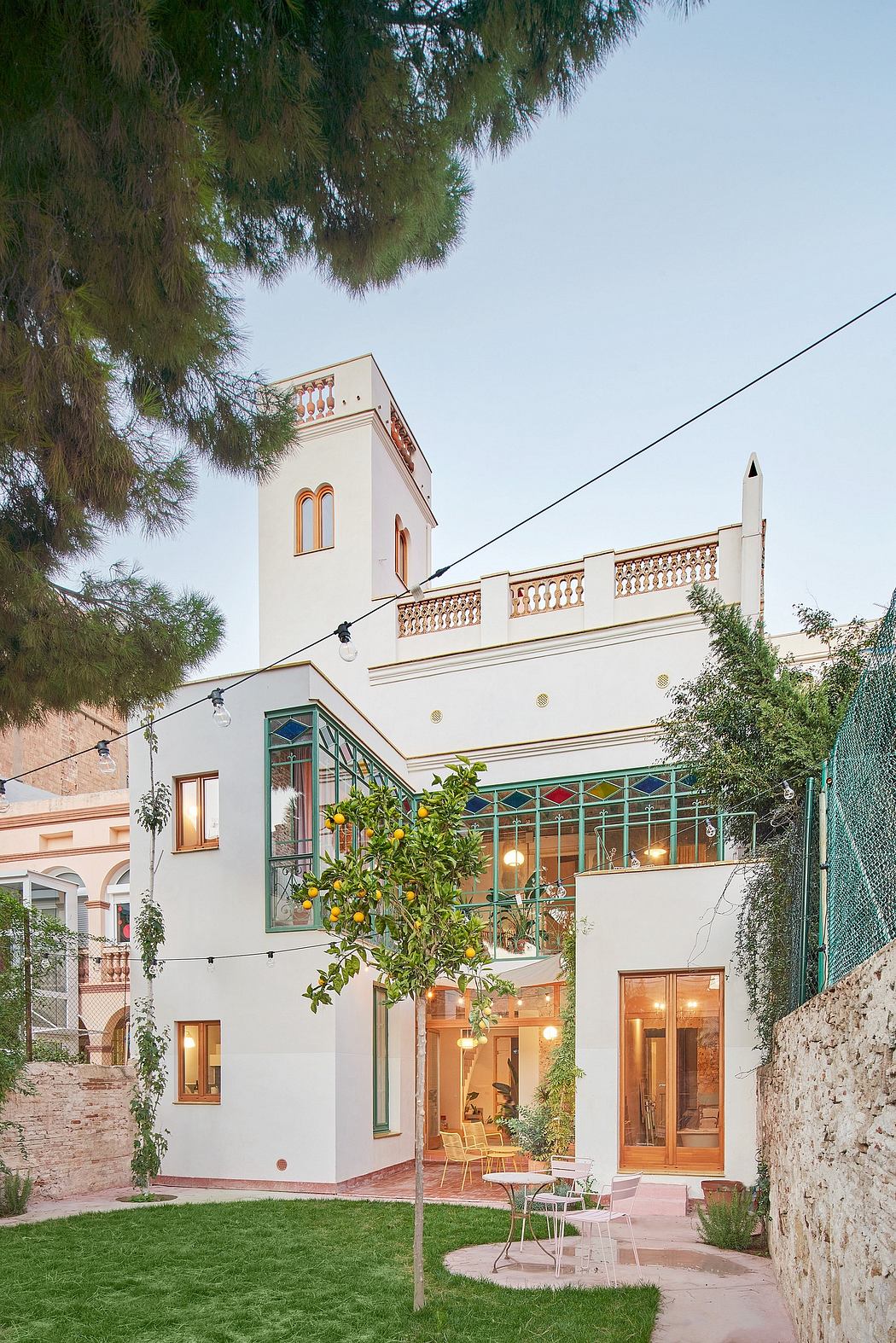 A stately villa with colorful leaded-glass windows, ornate balcony, and lush courtyard.