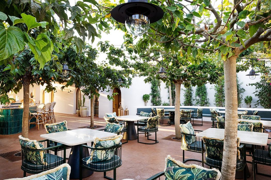 An inviting outdoor dining area surrounded by lush greenery, featuring stylish furniture and lighting.