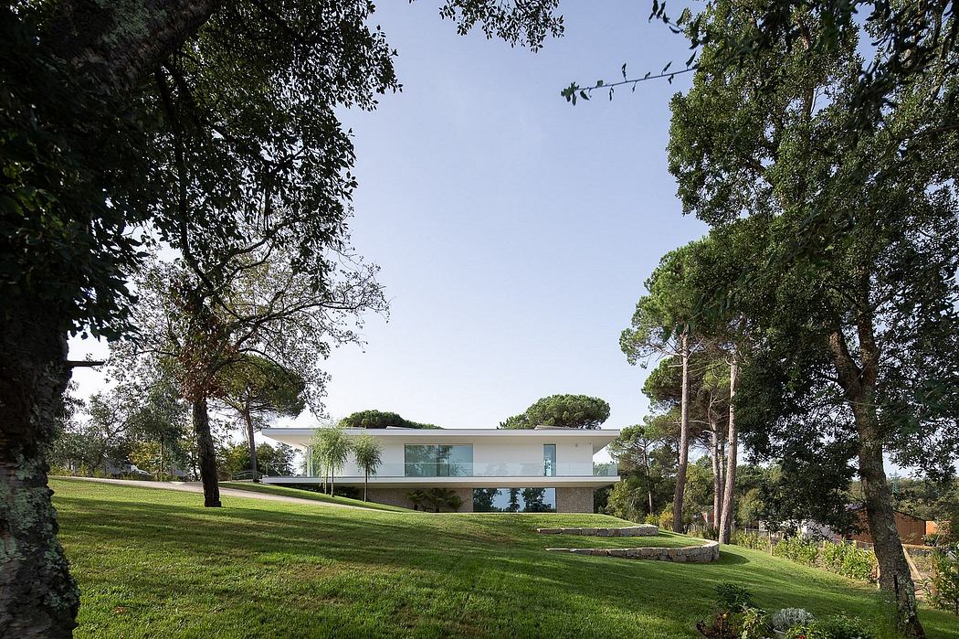 A modern, single-story home nestled among lush, verdant trees and landscaping.