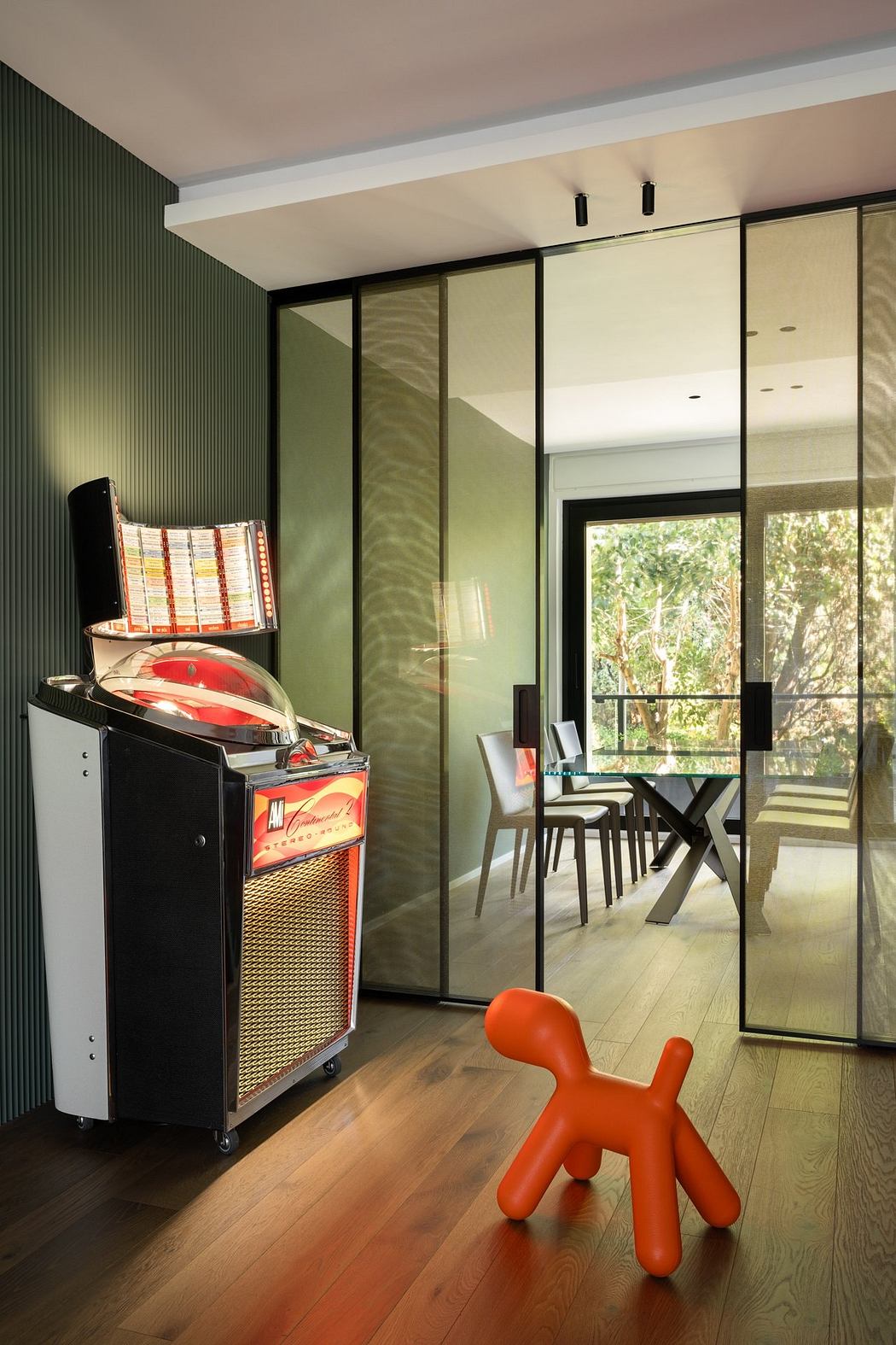 An interior with a black and green color scheme, a red child's chair, and a vintage jukebox.