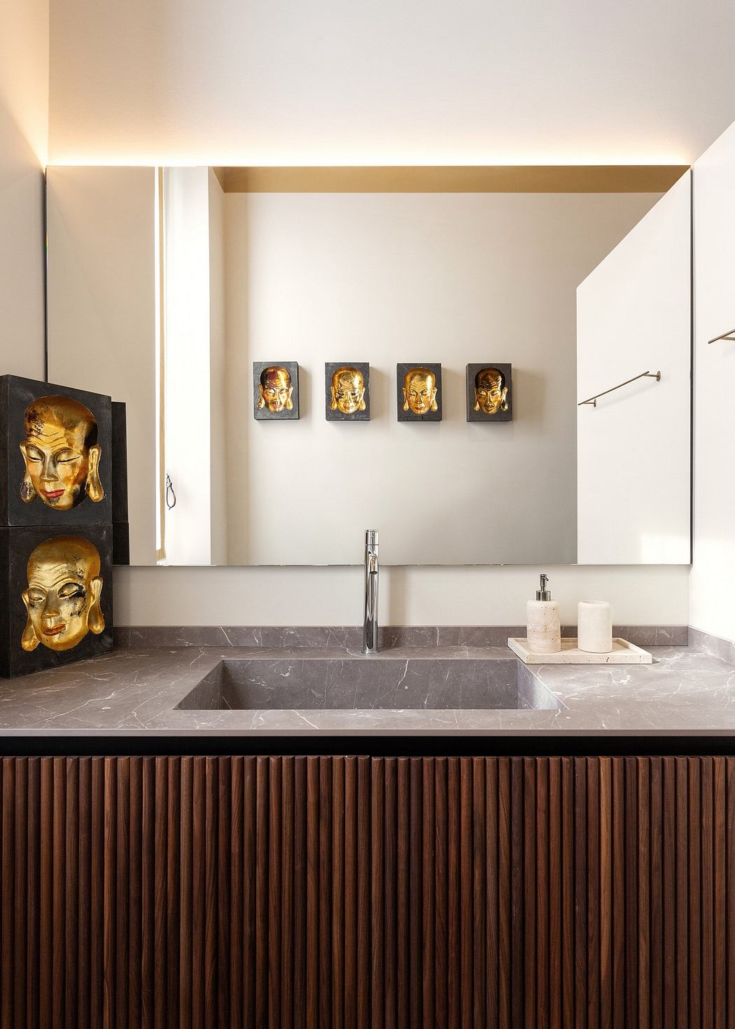 Elegant bathroom with marble vanity, gold Buddha sculptures, and wooden paneling.