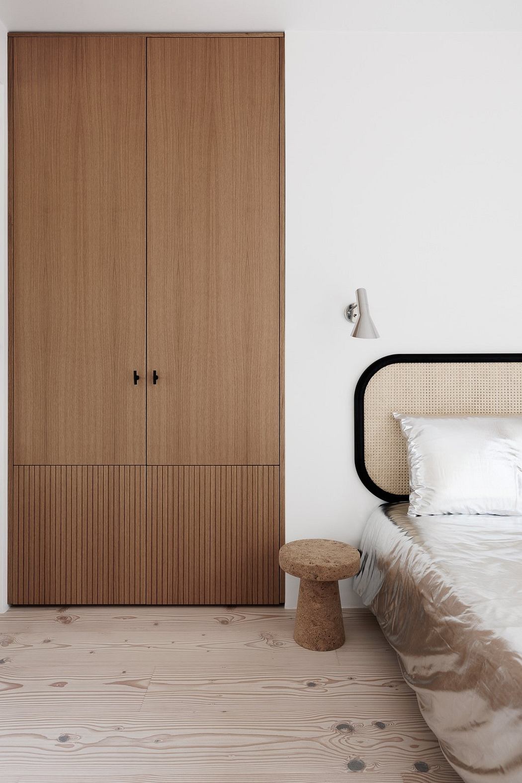 Wooden wardrobe, plush bedding, and natural wood flooring create a cozy, minimalist space.