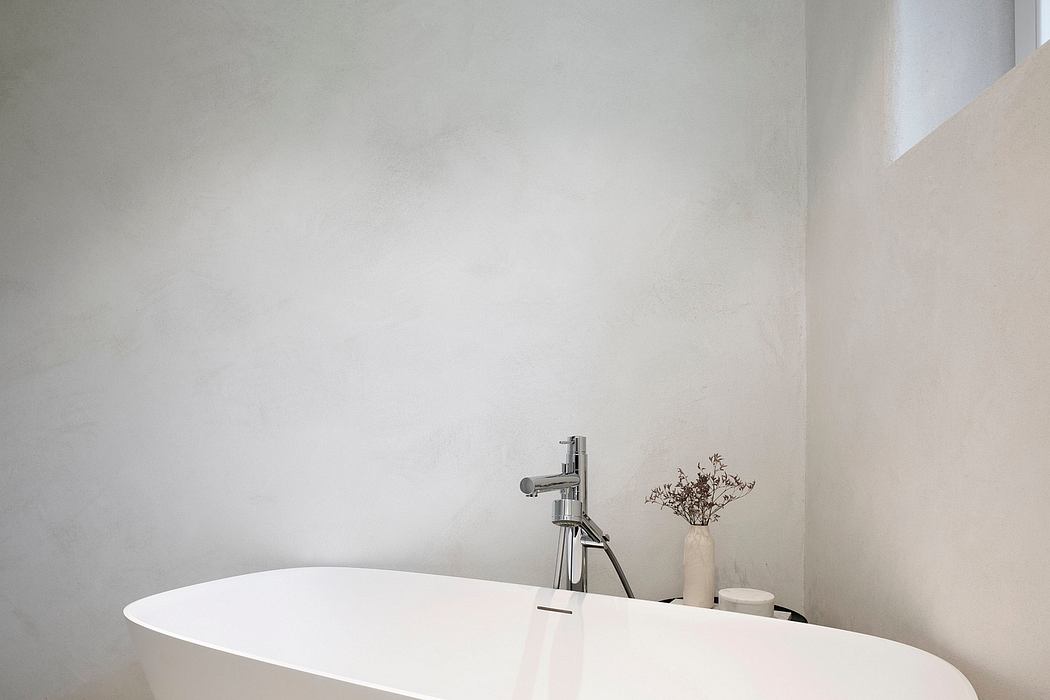 A minimalist bathroom with a simple faucet, decorative vase, and neutral color scheme.