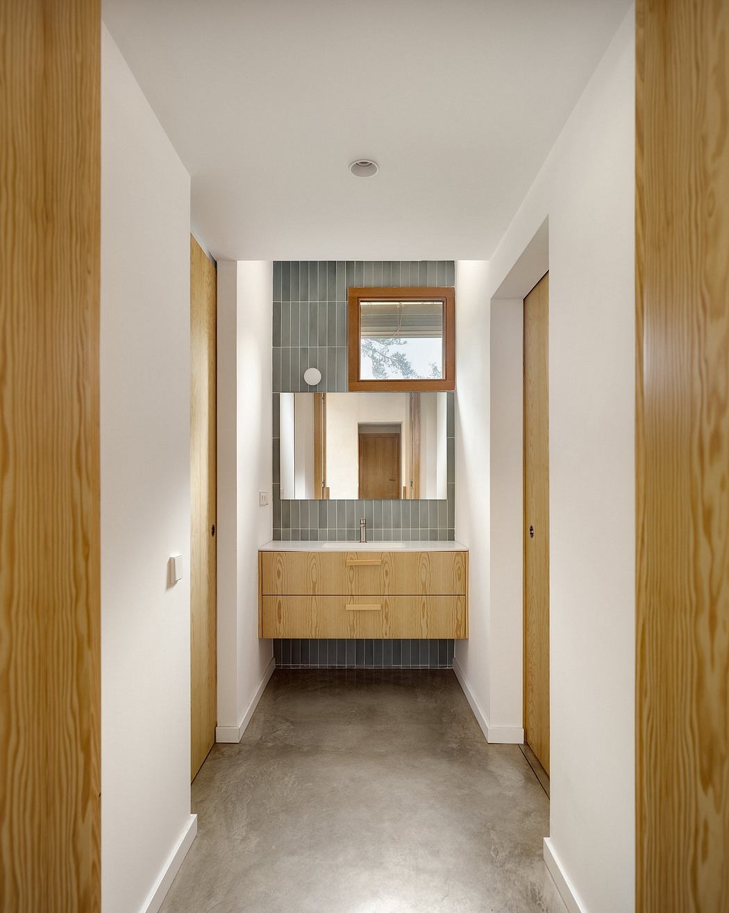 A modern, minimalist bathroom design featuring wood accents, grey tiles, and a floating vanity.