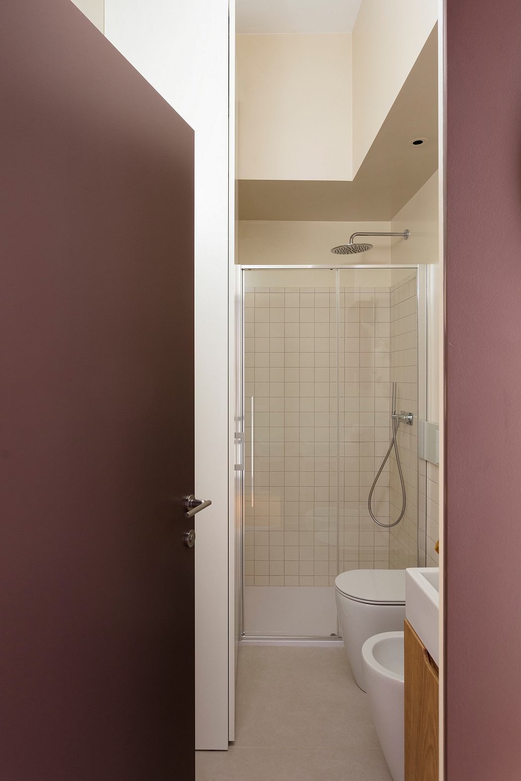 Minimalist bathroom with tiled shower, white fixtures, and contrasting dark walls.