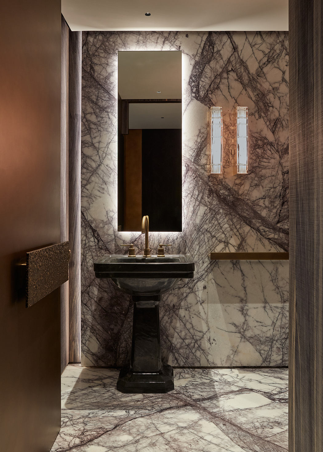 Exquisite marble bathroom with a striking pedestal sink, mirror, and elegant lighting.