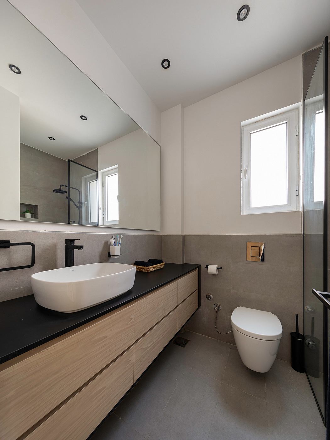 Sleek modern bathroom with wood vanity, vessel sink, and recessed lighting.