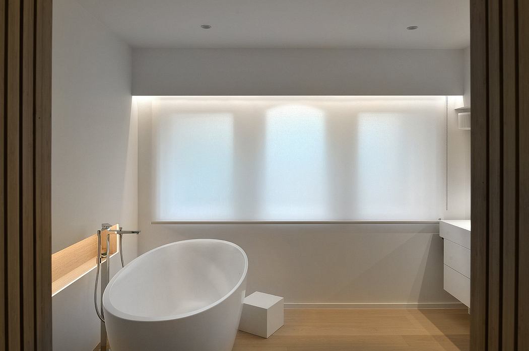 A modern, minimalist bathroom with a freestanding tub, wooden accents, and ample natural light.