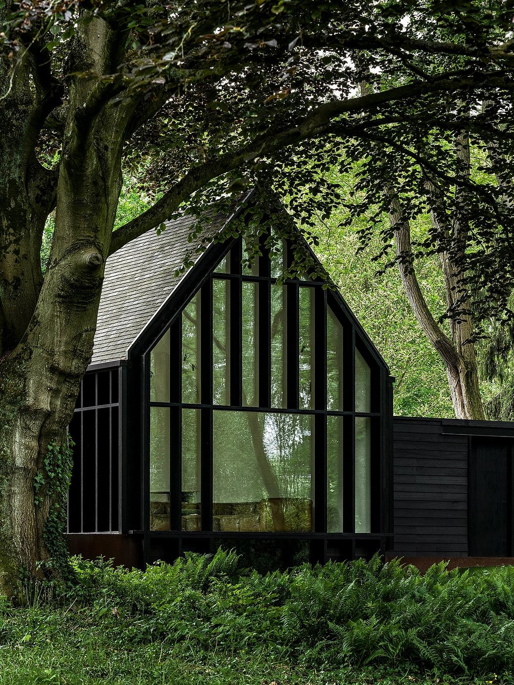 A striking glass cabin nestled amidst lush foliage, with a modern A-frame design and sleek black framing.