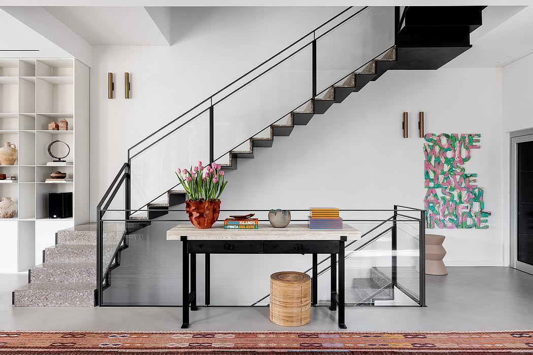 Sleek modern staircase with black metalwork, minimalist decor, and colorful graphic wall art.