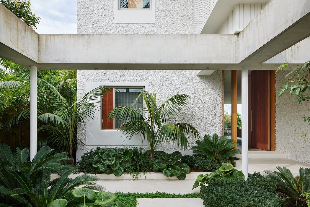 Tropical courtyard featuring lush vegetation, concrete architecture, and wooden accents.