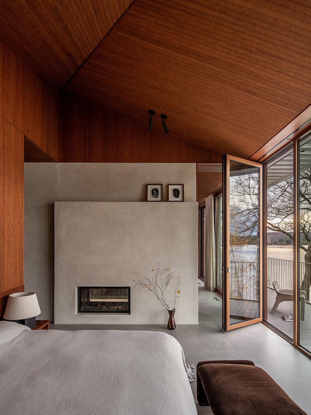 Warm wooden ceiling, concrete fireplace, and expansive glass doors leading to outdoor terrace.