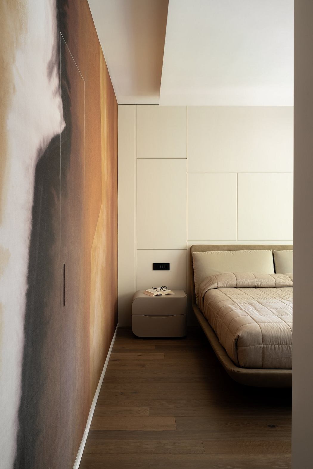 Minimalist bedroom with textured wall, wooden flooring, and cozy bedding.
