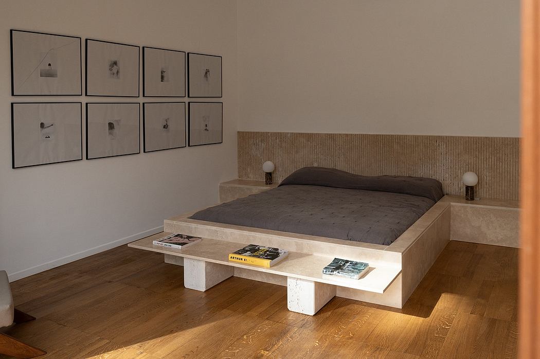 A modern, minimalist bedroom with a wooden platform bed and framed abstract art.