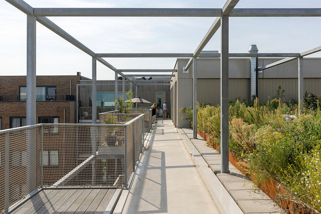 Elevated walkway with metal railings and overhead structure, surrounded by lush vegetation.