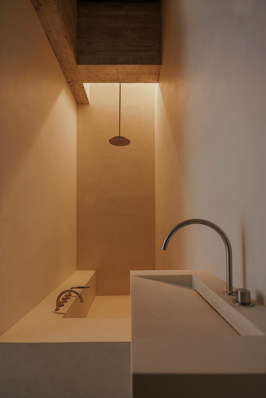 Warm, minimalist bathroom with recessed lighting, sleek faucet and sink design.