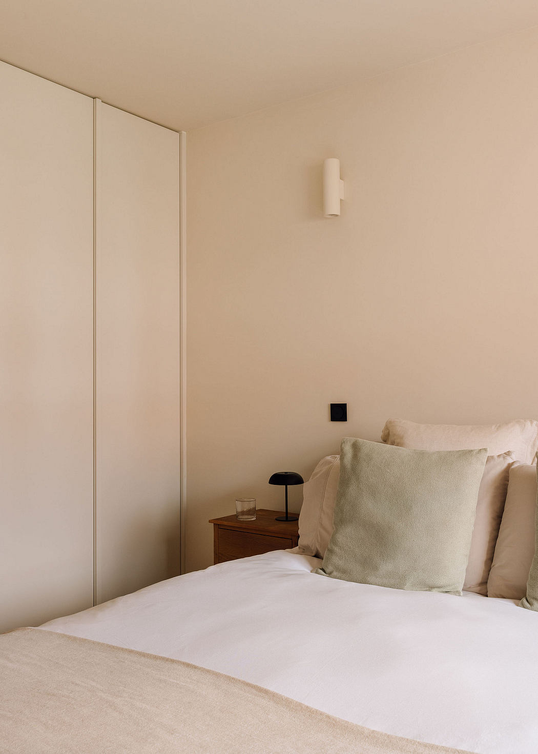 Minimalist bedroom with wooden nightstand, recessed lighting, and neutral-toned decor.
