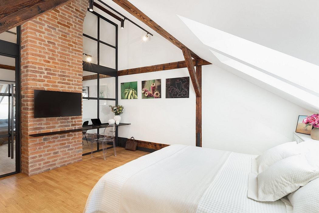 Cozy loft-like bedroom with exposed brick walls, wooden beams, and sleek furnishings.