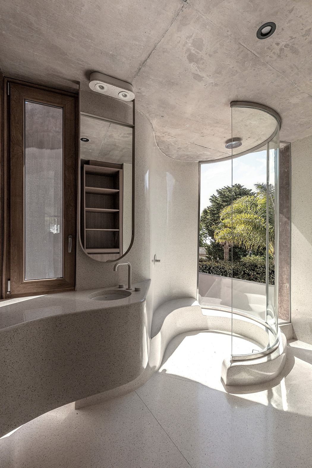 Sleek, minimalist bathroom design with curved glass shower and large window overlooking greenery.