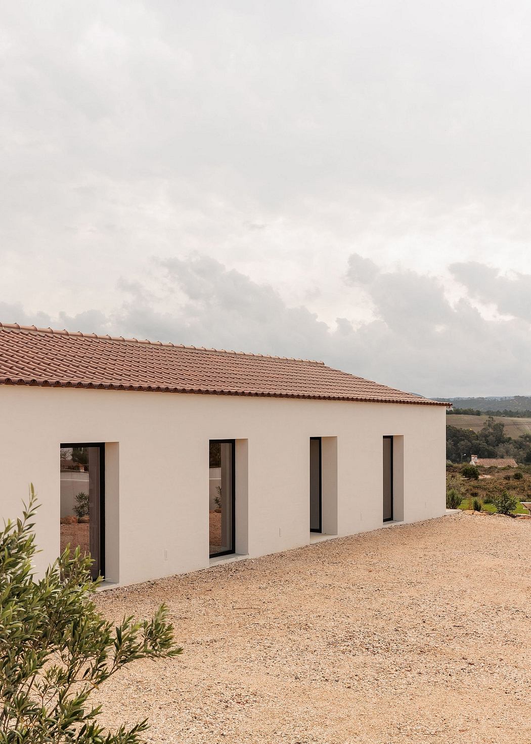 Architectural design featuring a modern, minimalist building with a tiled roof and large windows.